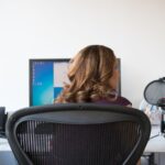 Adult woman working in a contemporary office setting with computer and microphone.