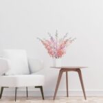 A modern minimalist living room scene featuring a white armchair, side table, and vase of flowers.