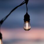 A serene close-up of hanging light bulbs against a twilight sky, capturing a calm evening ambiance.
