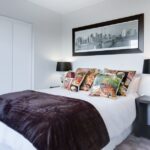 Stylish and contemporary bedroom featuring a cityscape artwork, colorful pillows, and modern decor.