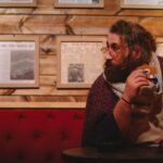 Man enjoying a snack and coffee in a warm, rustic café setting adorned with vintage newspapers.