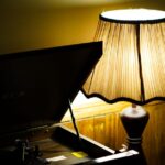 A dimly lit vintage setup featuring a gramophone and a warm glowing table lamp.