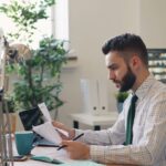 Focused man reviewing documents at a modern office desk with plants.