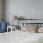 A serene modern bedroom featuring a comfy armchair and stylish lamps for a peaceful atmosphere.