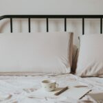Minimalist home office setup with laptop on bed, coffee cup, and notes for a comfortable work environment.