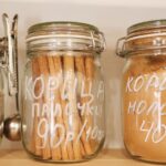 Glass jars on wooden shelves containing various spices, promoting zero waste and ethical shopping.