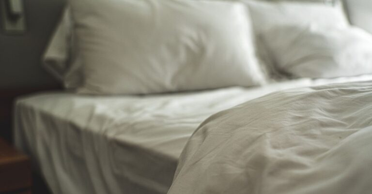 Elegant white bed linen with soft pillows creating a warm and inviting atmosphere.