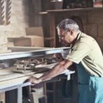 An artisan focuses on woodworking in a rustic indoor workshop, showcasing craftsmanship.