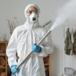 A person in full protective gear fumigates indoors for sanitization.