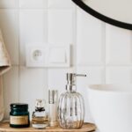 Interior of modern bathroom with various cosmetic products placed near sink with stylish faucet