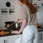 Woman cooking at stove in a cozy modern kitchen setting.