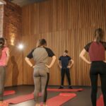 A diverse group stretching together in a contemporary gym with wooden detailing.