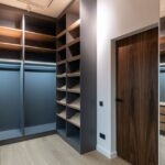 Interior of spacious light wardrobe room with empty shelves near mirror and door