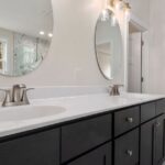 Elegant bathroom interior featuring round mirrors and contemporary vanity.