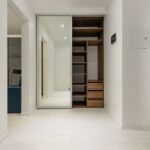 Contemporary corridor interior with empty shelves in closet with mirror reflecting floor and lamps at home