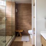 Elegant and modern bathroom featuring a glass shower, wooden accents, and a sleek sink design.