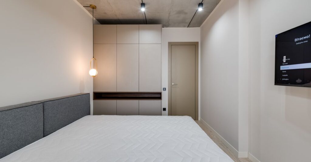 A sleek and modern minimalist bedroom featuring a bed, furniture, and ambient lighting.