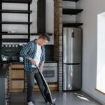 A man cleaning the modern kitchen with a vacuum cleaner, showcasing contemporary interior design.