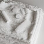 Elegant arrangement of white towels and beauty products in a clean, minimalist setting.