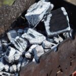 A detailed close-up of charred coals in an outdoor grill, showcasing high heat and barbecue readiness.