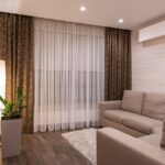 A stylish and cozy living room featuring a sofa, wooden flooring, and soft lighting.