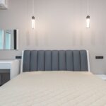 Sleek minimalist bedroom design featuring a plush bed, pendant lighting, and modern furnishings.