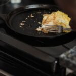 Man cooking omelet in a pan on a stove, showcasing a home-cooked meal setting.