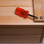 A close-up of a screwdriver on a wooden box, highlighting DIY and home improvement tools.