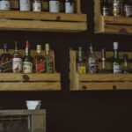 A rustic wooden shelf display of liquor bottles on a dark wall, perfect for a bar setting.