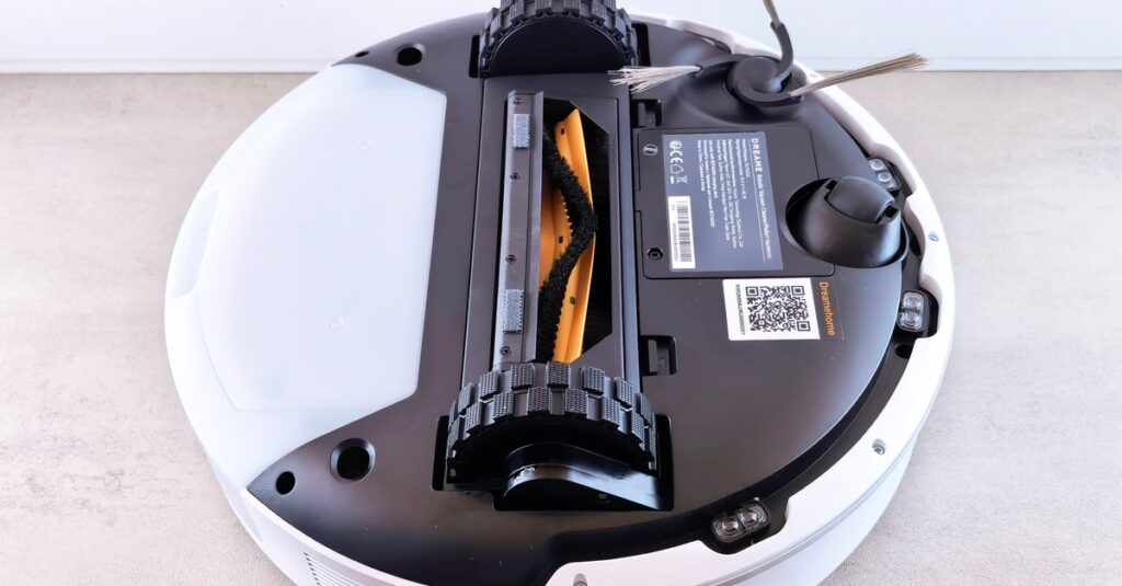 Close-up view of a robotic vacuum cleaner's underside displaying brushes and sensors.