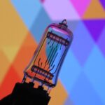 Glass tube against a colorful geometric abstract background, vivid hues.